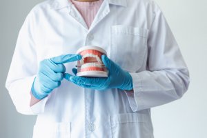 image of a dentist in a white lab coat holding a denture